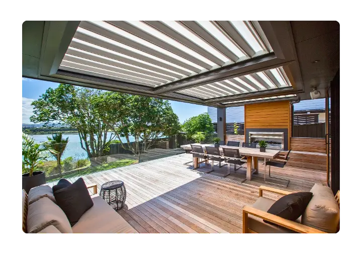Expansive modern deck with a louvered roof system, outdoor furniture, and ocean views.