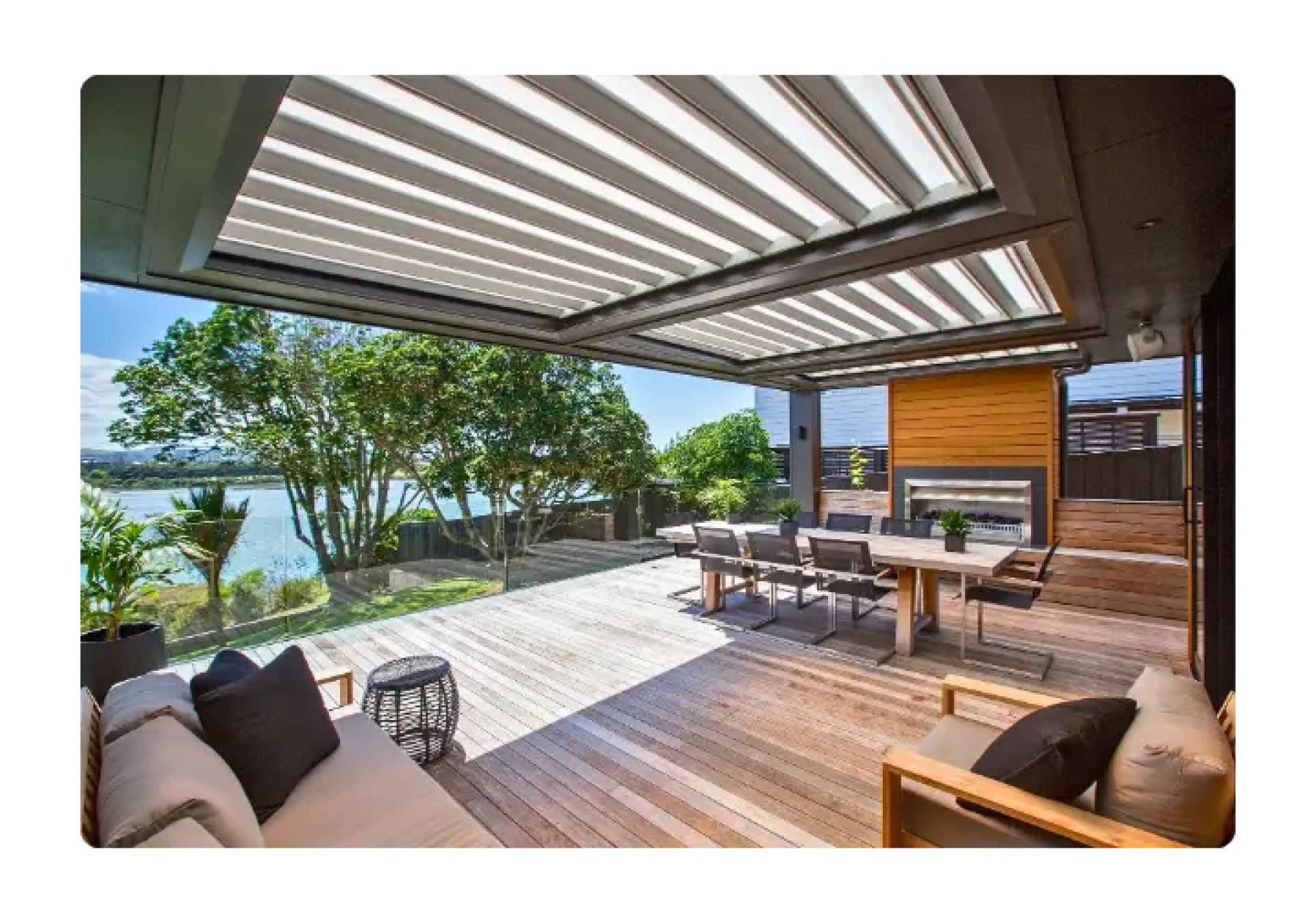 Expansive modern deck with a louvered roof system, outdoor furniture, and ocean views.